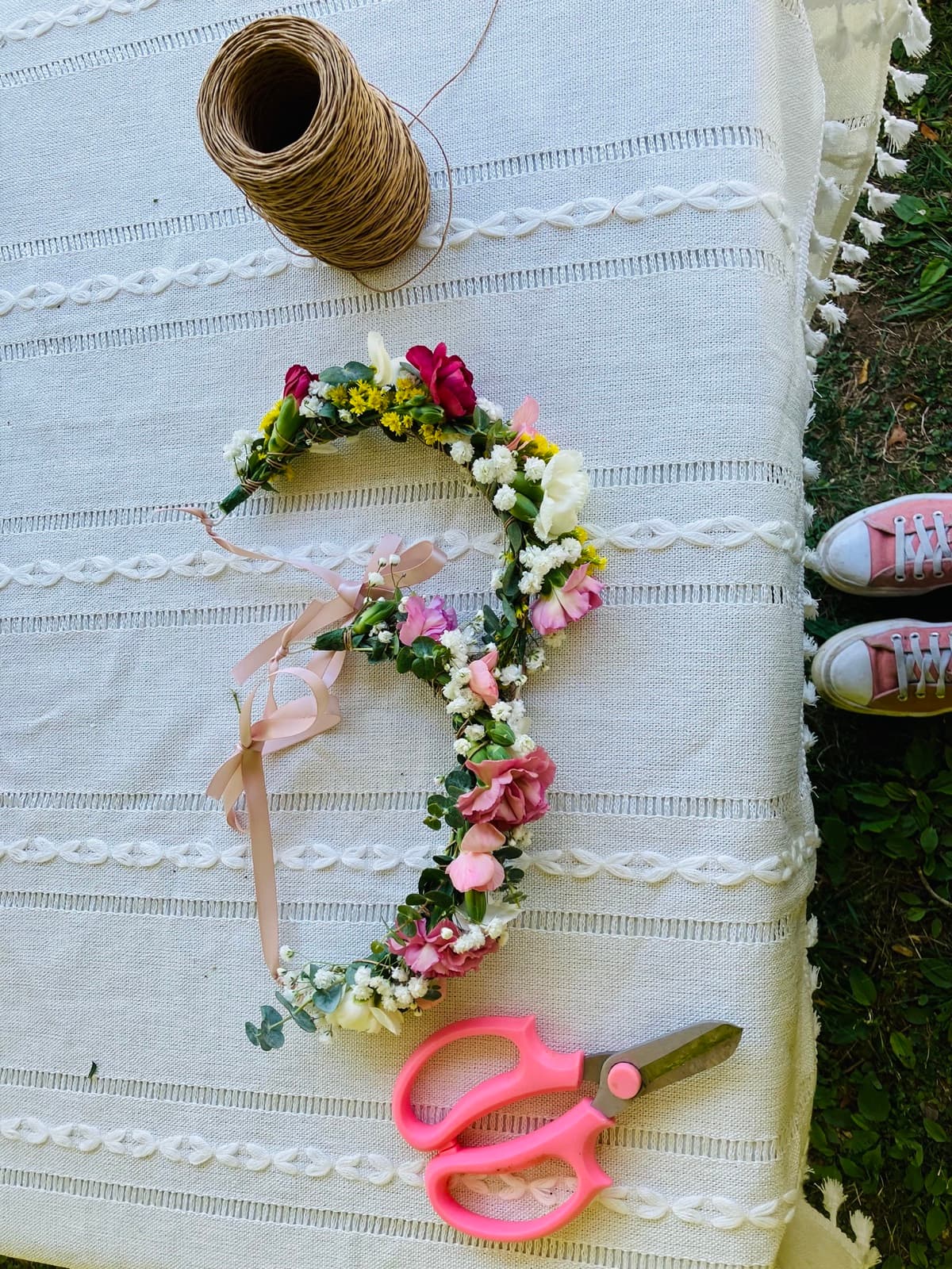 Flower crown in progress laid flat with scissors and twine — the craft in progress at The Flower Station